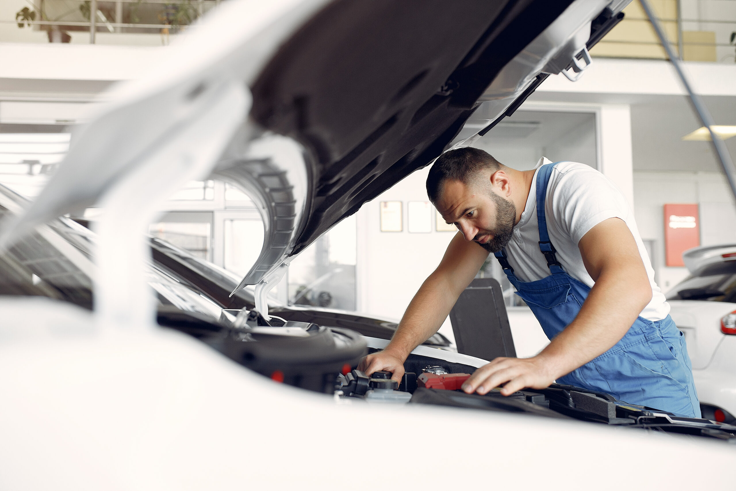 Worker in a car salon. Expert checks the car. Man in a blue uniform.