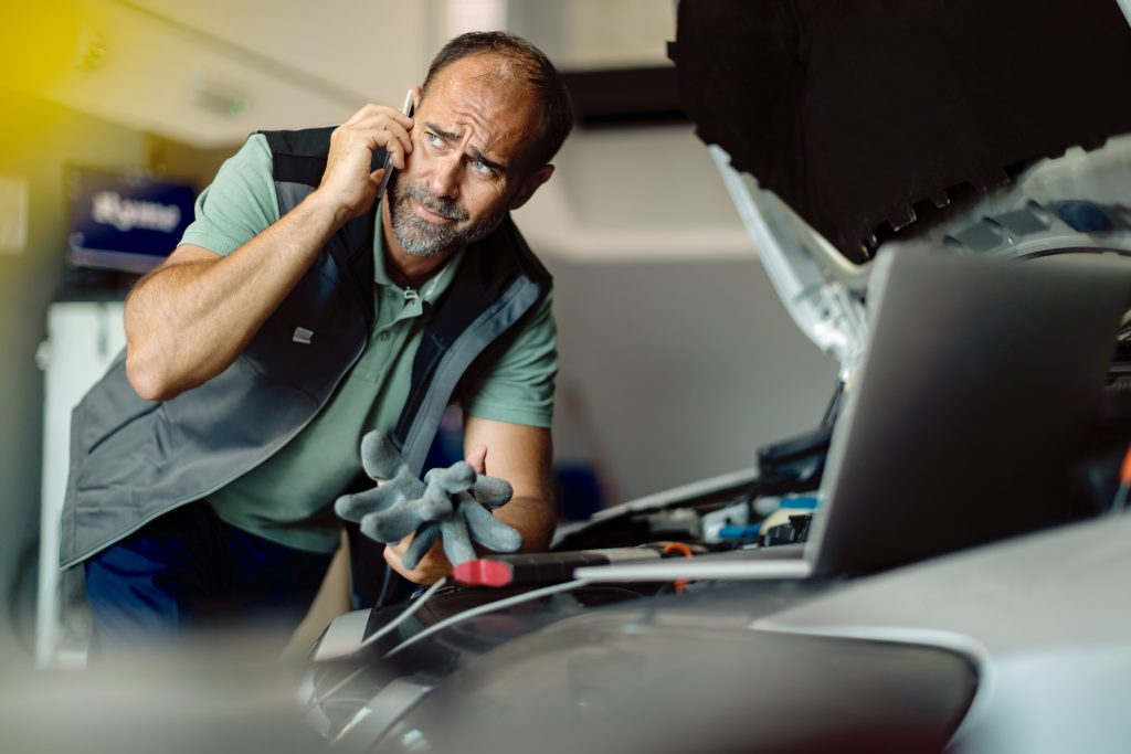 Auto repairs man talking on the phone while working in a worksho